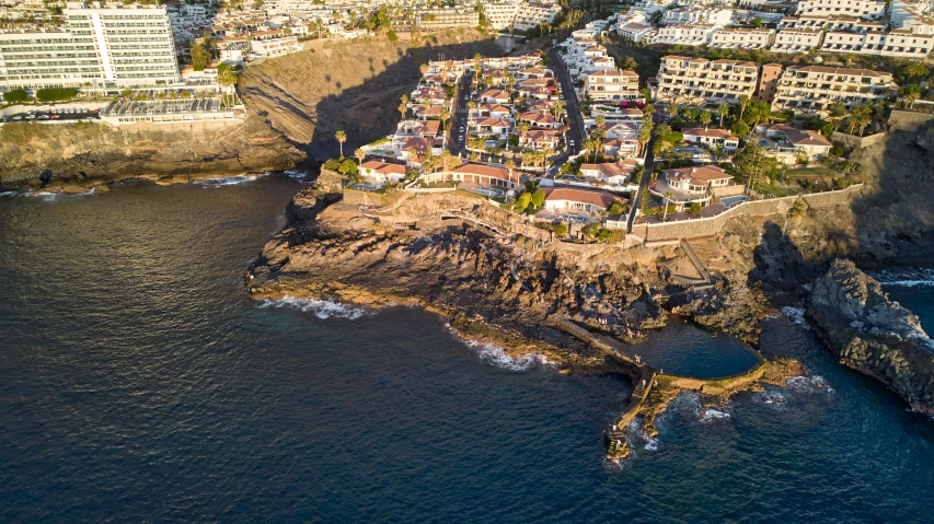 an aerial view of a city next to the ocean, by Tom Wänerstrand, pexels contest winner, cliff side, promo image, brown, neighborhood