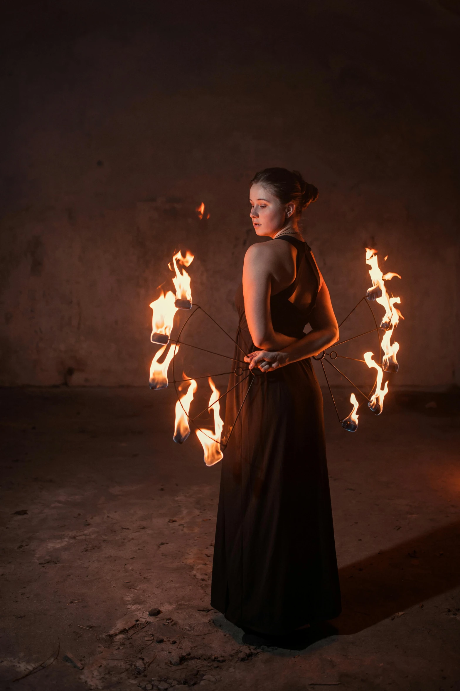 a woman standing in a dark room with fire in her hands, twirling, square, profile image, trending photo