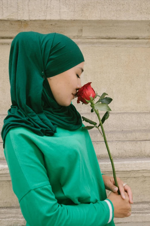 a woman in a hijab smelling a rose, green shirt, curated collections, viridian and venetian red, romantic lead