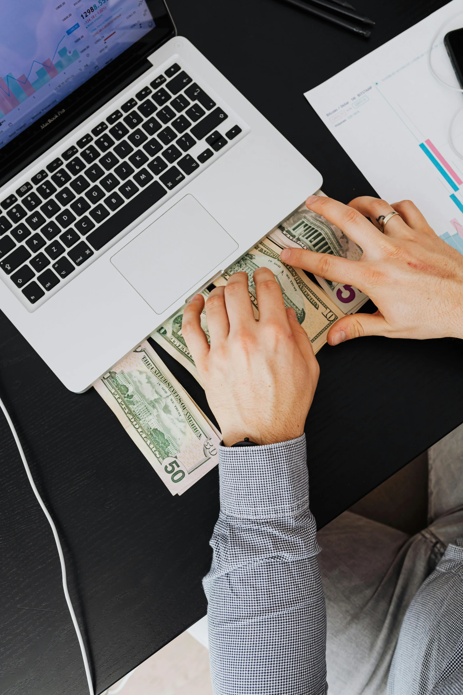 a man sitting at a desk with a laptop and money, by Byron Galvez, trending on unsplash, lgbtq, 15081959 21121991 01012000 4k, plain background, a high angle shot