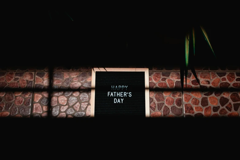 a sign that says happy father's day in front of a brick wall, unsplash, dark mood lighting, photo of the cinema screen, glowforge template, dark. no text