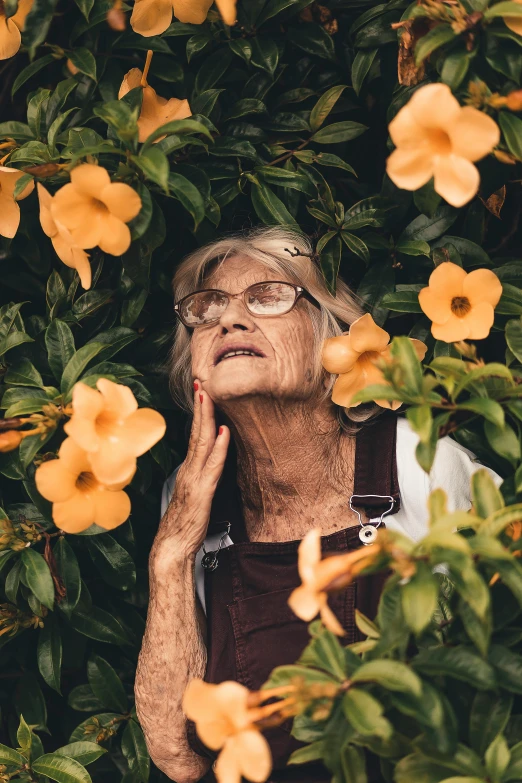 an older woman in a garden surrounded by flowers, by Elsie Few, pexels contest winner, wrinkly forehead, on a yellow canva, as she looks up at the ceiling, instagram photo