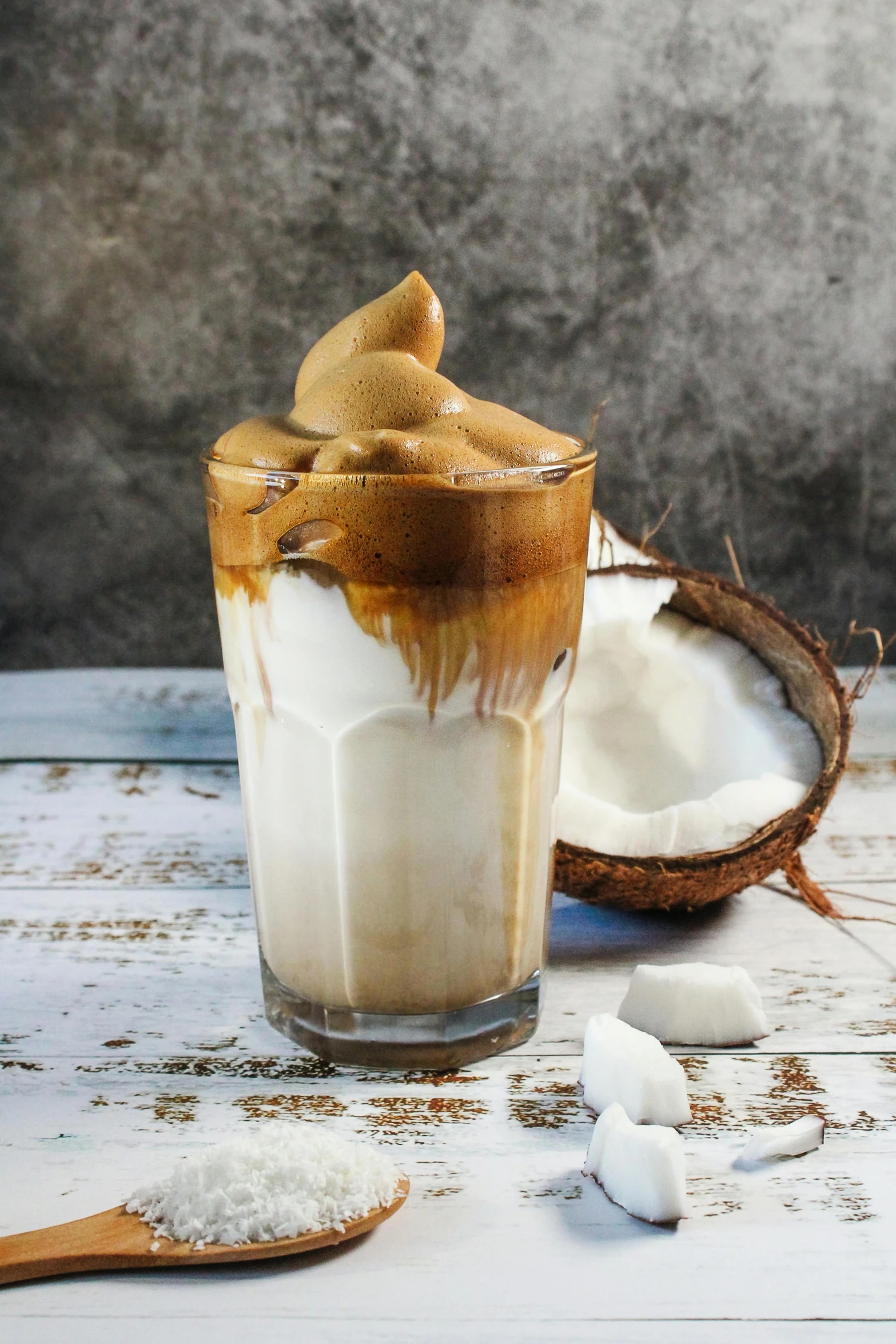 a glass of ice cream sitting on top of a wooden table, coconuts, iced latte, thumbnail, milkshake