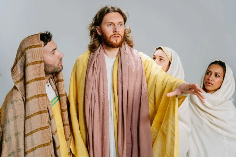 a group of people standing next to each other, unsplash, renaissance, dressed like jesus christ, yellow robe, annoyed, ( ( theatrical ) )