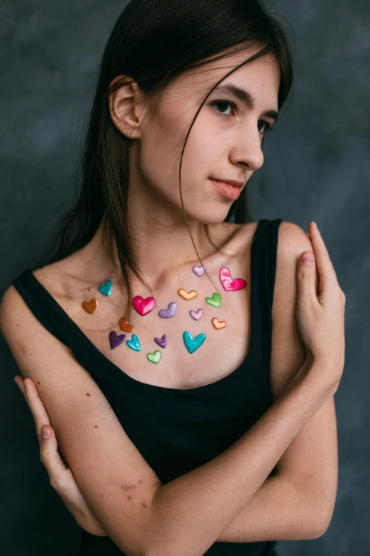 a woman with hearts painted on her chest, a colorized photo, by Julia Pishtar, trending on pexels, wearing several pendants, made of silk paper, official product photo, glitter sticker