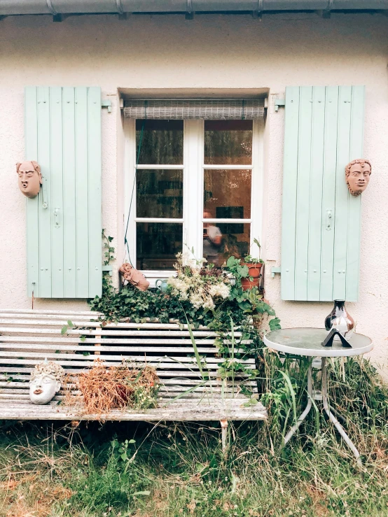 a bench in front of a house with green shutters, by Adélaïde Victoire Hall, unsplash, visual art, pale blue faces, taken on iphone 14 pro, cat on a windowsill, with a french garden