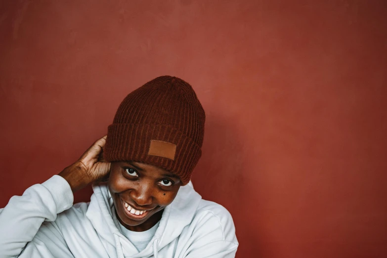 a close up of a person wearing a hat, a character portrait, inspired by Afewerk Tekle, trending on pexels, hurufiyya, reddish - brown, dramatic smiling pose, beanie, male teenager