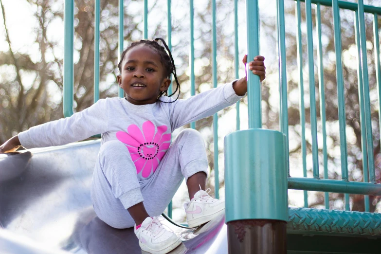 a little girl sitting on top of a slide, by Winona Nelson, pexels contest winner, wearing a track suit, african american girl, grey, flower power