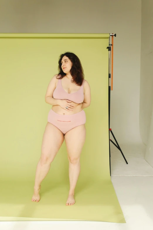 a woman standing in front of a green backdrop, pale pink bikini, bbw, gif, lynn skordal