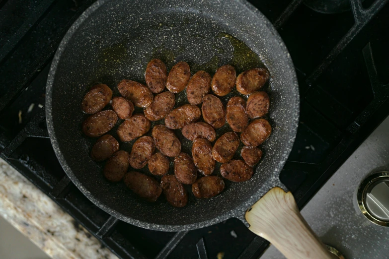 a frying pan filled with meat sitting on top of a stove, product image, chorizo sausage, epicurious, nugget