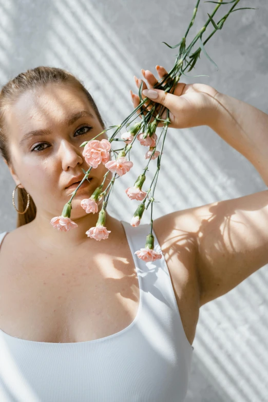a woman holding a bunch of flowers in front of her face, inspired by Elsa Bleda, unsplash, renaissance, alluring plus sized model, wearing a low cut tanktop, portrait of florence pugh, on a white table