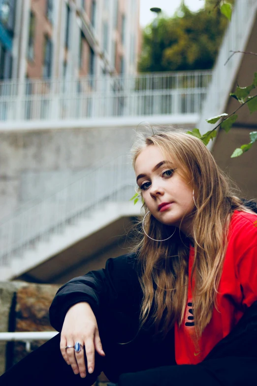 a woman sitting on a ledge with a skateboard, an album cover, unsplash, portrait of kim petras, looking serious, wearing red jacket, portrait featured on unsplash