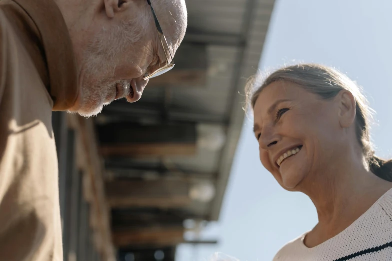 a man and a woman standing next to each other, pexels contest winner, photorealism, smiling at each other, nearest neighbor, looking upwards, an oldman