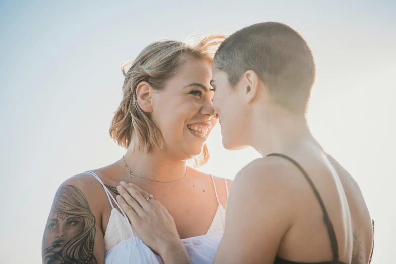 a man and a woman standing next to each other, a photo, by Lee Loughridge, unsplash, lesbian embrace, shaved hair, two beautiful women in love, pr shoot