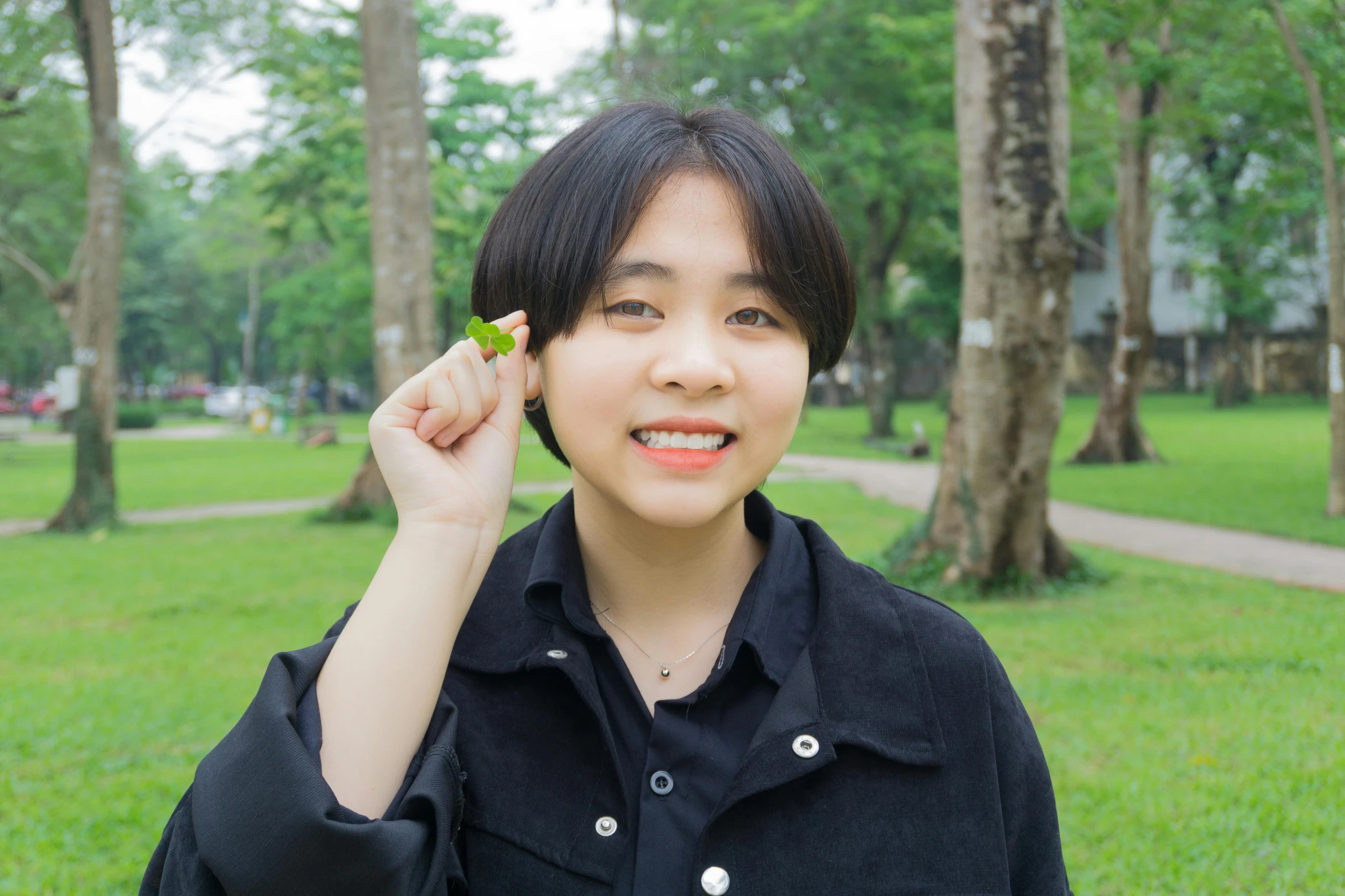 a woman standing in a park with a leaf in her hand, an album cover, inspired by Kim Jeong-hui, pexels contest winner, young cute wan asian face, scientific photo, smol, protophyta