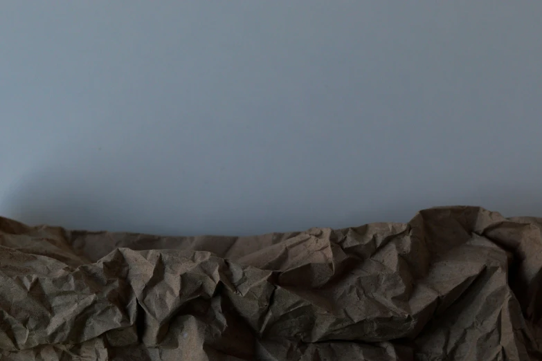 a brown paper bag sitting on top of a bed, by Anna Füssli, visual art, background image, chocolate. rugged, blue / grey background, cave wall