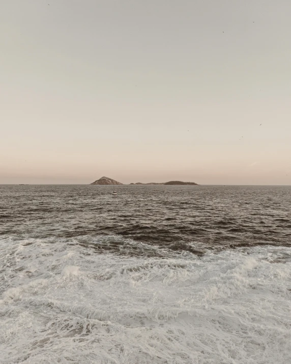 a large body of water with a small island in the distance, unsplash contest winner, romanticism, slightly tanned, faded glow, two medium sized islands, low quality photo