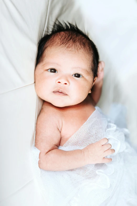 a close up of a baby laying on a bed, by Robbie Trevino, happening, darren quach, canvas, portait image