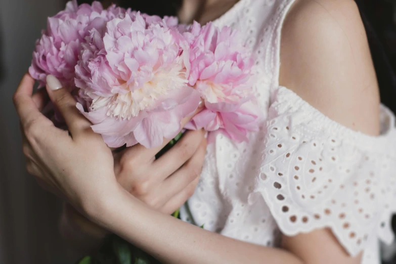a woman holding a bunch of pink flowers, pexels contest winner, wearing white camisole, peony flowers, upper body image, subtle detailing
