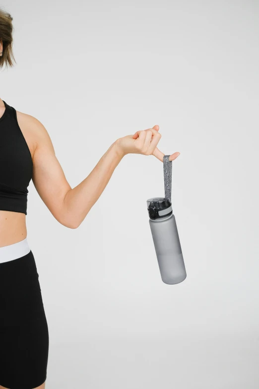 a woman in a sports bra top holding a water bottle, by Nina Hamnett, unsplash, minimalism, grey, arms out, with small object details, on clear background