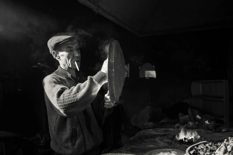 a black and white photo of a man smoking a cigarette, a black and white photo, by andrei riabovitchev, pexels contest winner, process art, cooking pizza, mongol, fan favorite, holding a baguette