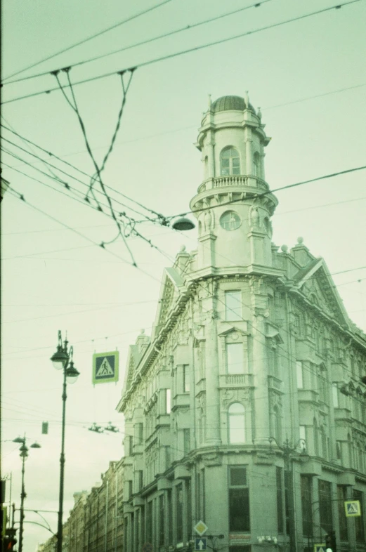 a very tall building sitting on the side of a street, a polaroid photo, inspired by Alexey Venetsianov, art nouveau, turrets, photo taken on fujifilm superia, trams ) ) ), pale colors