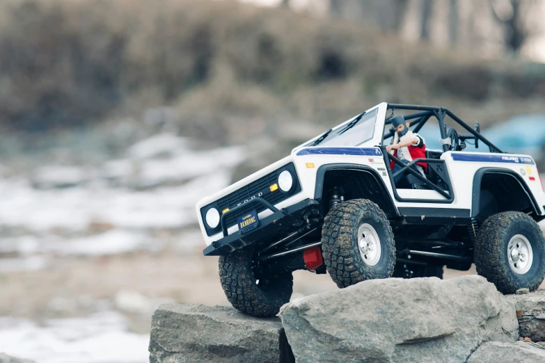 a toy truck that is sitting on a rock, by karlkka, unsplash, photorealism, off-roading, valiant, action shot, well built