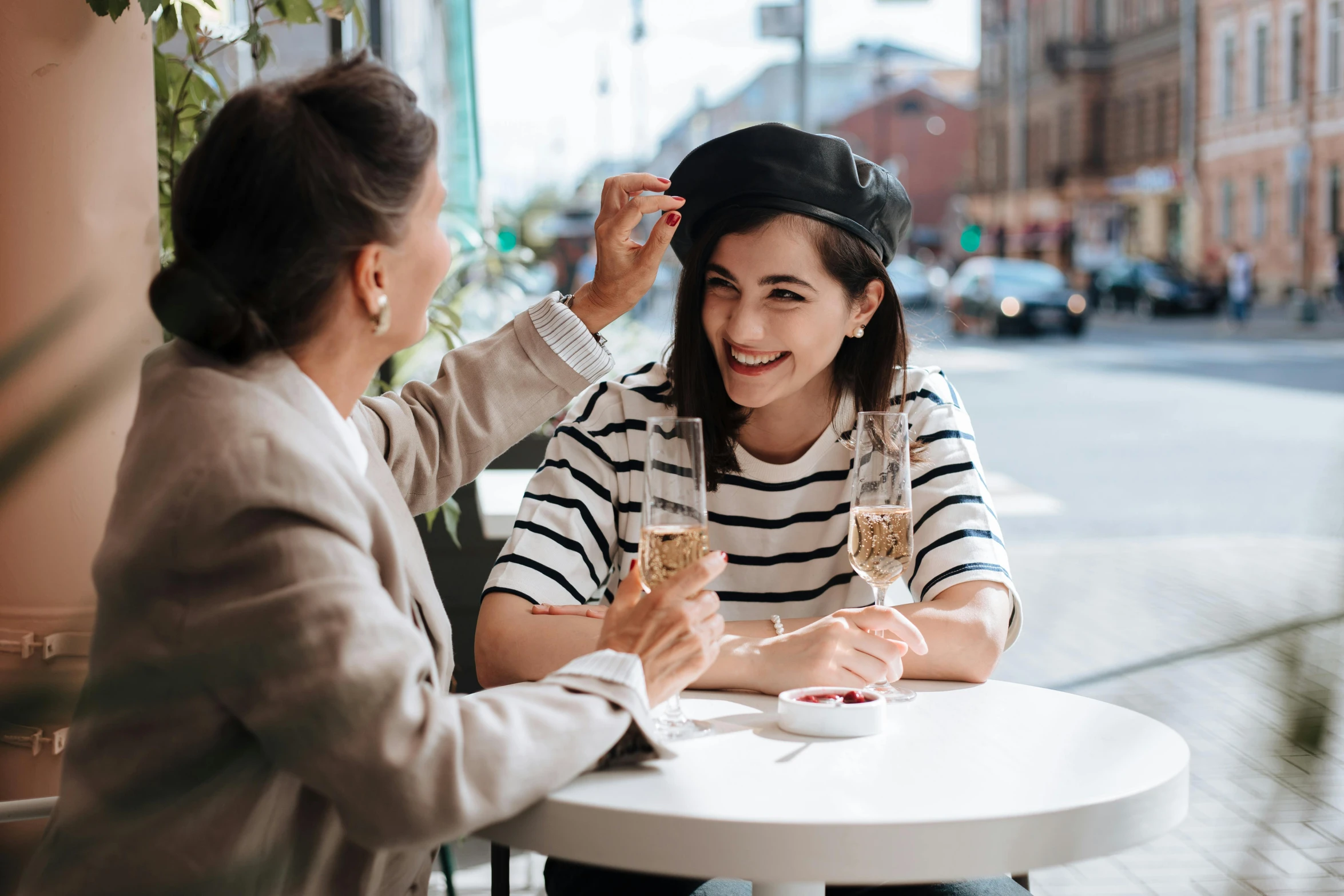 a woman sitting at a table with a glass of wine, cute hats, reaching out to each other, 2019 trending photo, wearing a beret