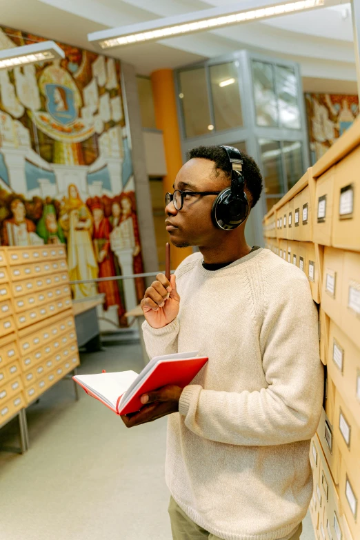 a man standing in a library holding a book, an album cover, pexels contest winner, academic art, wearing headset, inspect in inventory image, holy themed, ethnography