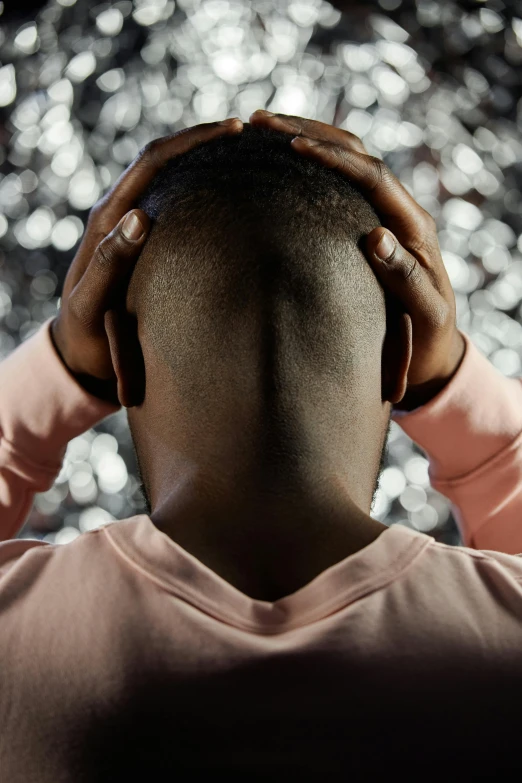 a man with his hands on his head, trending on pexels, glittery, black teenage boy, hunched shoulders, shaved hair