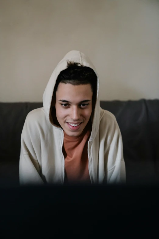 a man in a hoodie sitting on a couch, reddit, happening, lovely smile, avatar image, non binary model, webcam footage