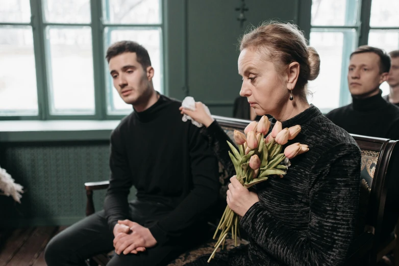 a woman sitting on a bench holding a bunch of flowers, a portrait, by Zofia Stryjenska, pexels contest winner, sad men, woman holding another woman, ( ( theatrical ) ), concert