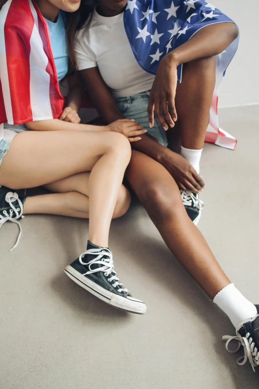 a couple of women sitting next to each other, trending on unsplash, hyperrealism, boy shorts, converse, patriotism, black teenage boy