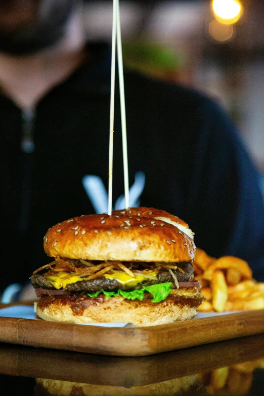 a large hamburger sitting on top of a wooden cutting board, a portrait, unsplash, serving fries, melbourne, 2 5 yo, profile image