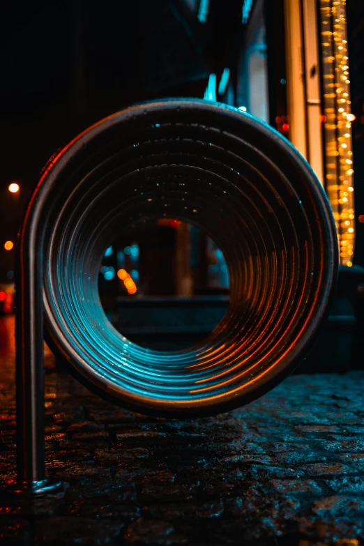 a large metal tube sitting on top of a sidewalk, by Adam Marczyński, pexels contest winner, kinetic art, complementary rim lights, heated coils, vinyl material, circle