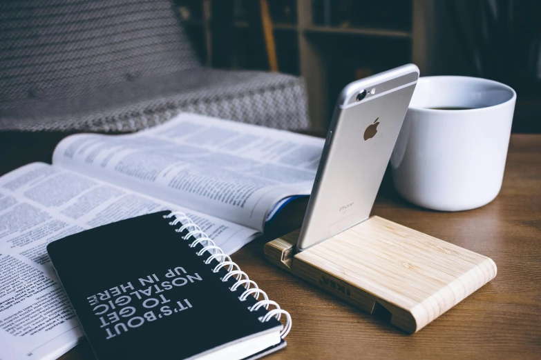 a cell phone sitting on top of a book next to a cup of coffee, trending on unsplash, happening, wooden platforms, 9 9 designs, light wood, black