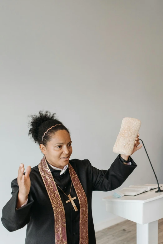 a woman giving a speech at a podium, an album cover, unsplash, dressed like a cleric, bread, diverse, hand on table