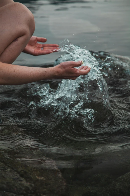 a person kneeling on a rock in a body of water, inspired by Elsa Bleda, pexels contest winner, renaissance, partially cupping her hands, hydration, rushing water, dry skin