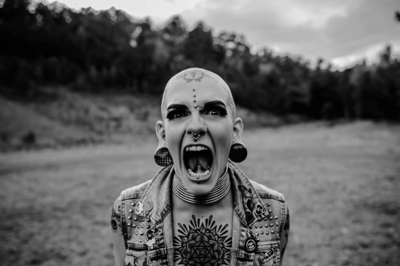 a black and white photo of a man with tattoos on his body, by Emma Andijewska, pexels contest winner, lowbrow, angry female alien, with wide open mouth, shaved head, solar punk