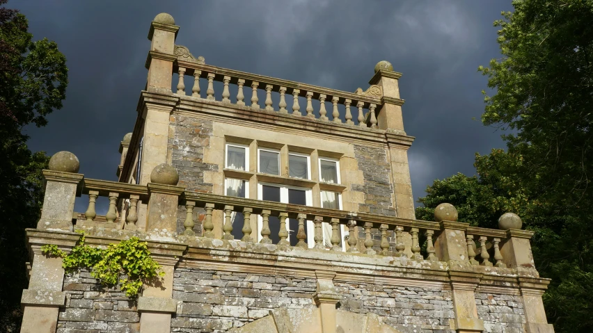 a stone building with a dark sky in the background, renaissance, balcony, gwyn, rich estate, slightly sunny weather
