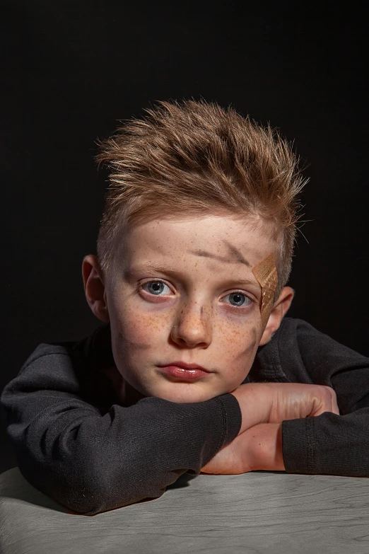 a young boy sitting at a table looking at the camera, an album cover, by Lee Gatch, pexels contest winner, hyperrealism, lightning bolt scar on forehead, prosthetic makeup, posing for a fight, on black background