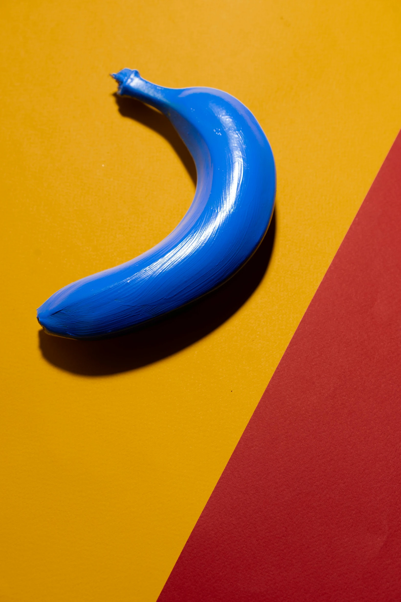 a blue banana sitting on top of a yellow and red surface, by Doug Ohlson, rubber and latex, crescent moon, close-up shoot, cobalt blue