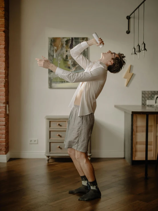 a man standing on top of a hard wood floor, spilling juice, wearing a light shirt, tiktok video, leonid