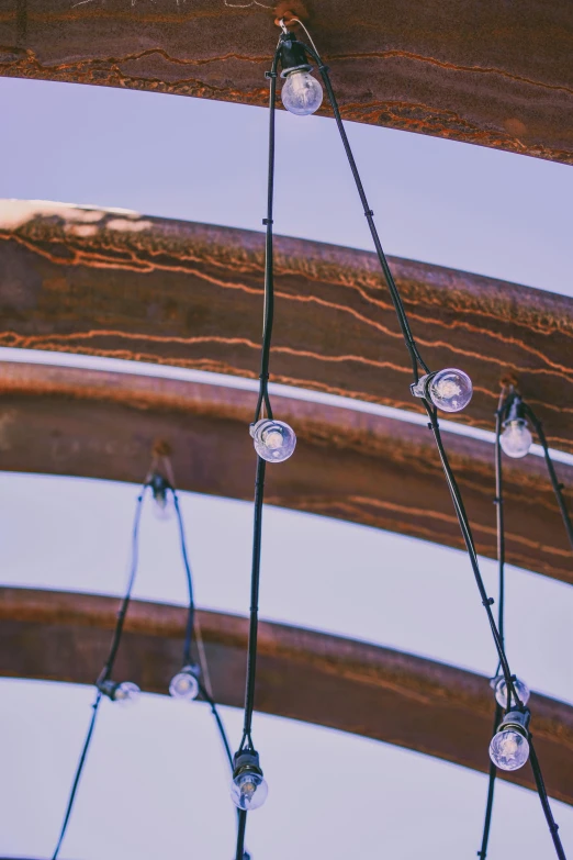 a bunch of lights hanging from a wooden structure, an abstract sculpture, unsplash, morning detail, steel archways, trending photo, circles