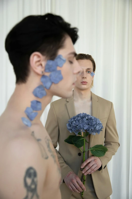 a man standing in front of a mirror holding a flower, an album cover, inspired by Jean Malouel, pexels contest winner, attractive androgynous humanoid, blue flowers, profile image, luka mivsek