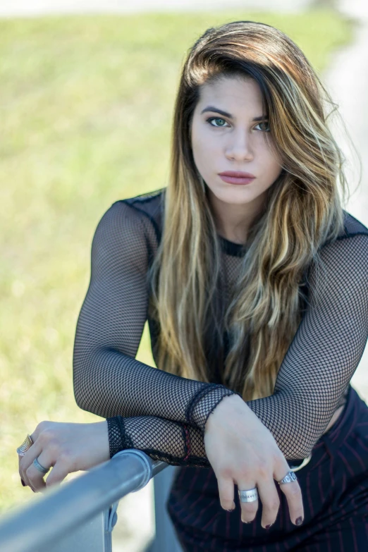 a beautiful young woman sitting on a rail, a portrait, inspired by Elsa Bleda, unsplash, fishnet clothes, square, black top, in a grassy field