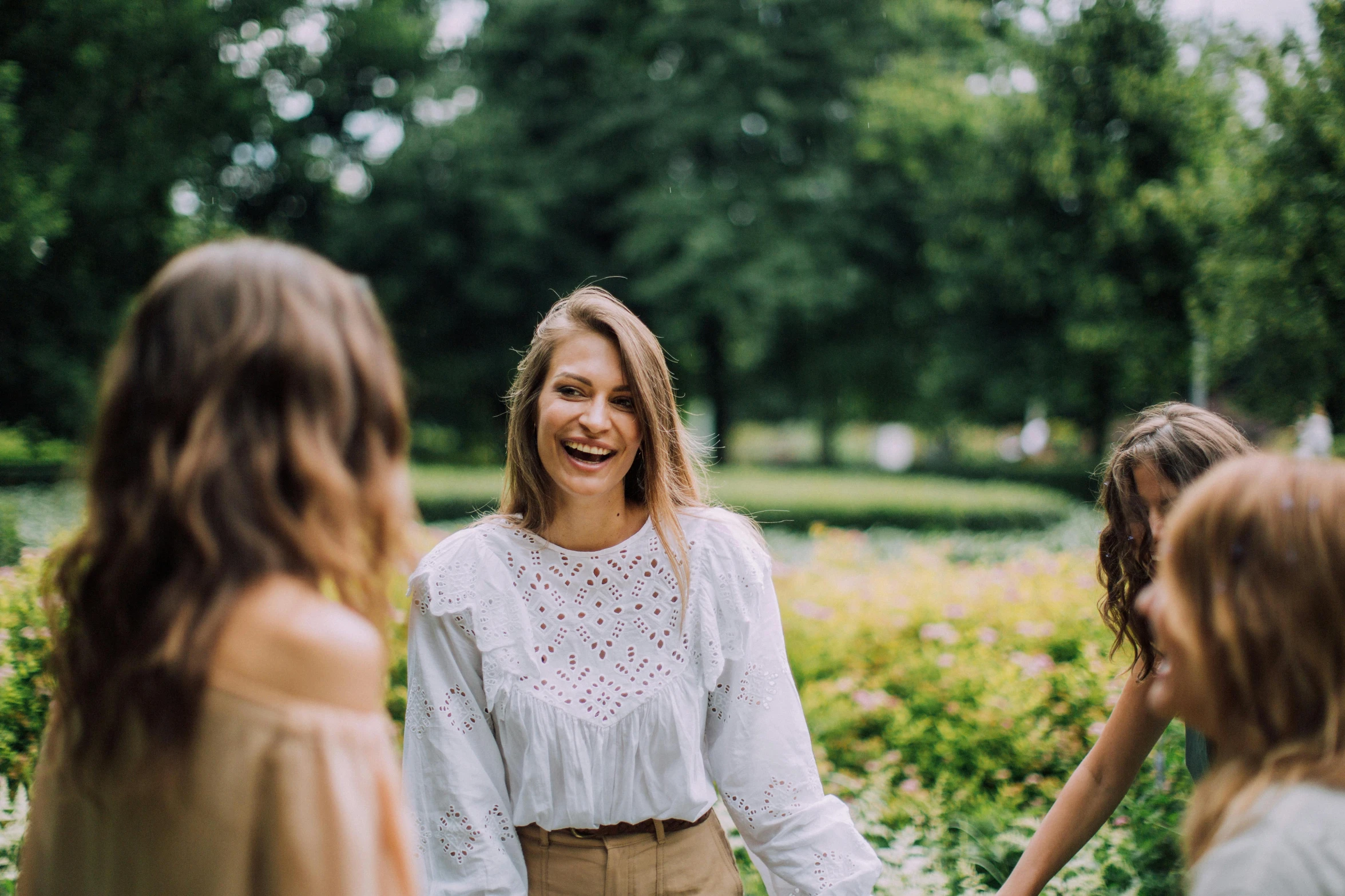 a group of women holding hands in a park, pexels contest winner, happening, smiling girl, wearing a blouse, product introduction photo, looking across the shoulder