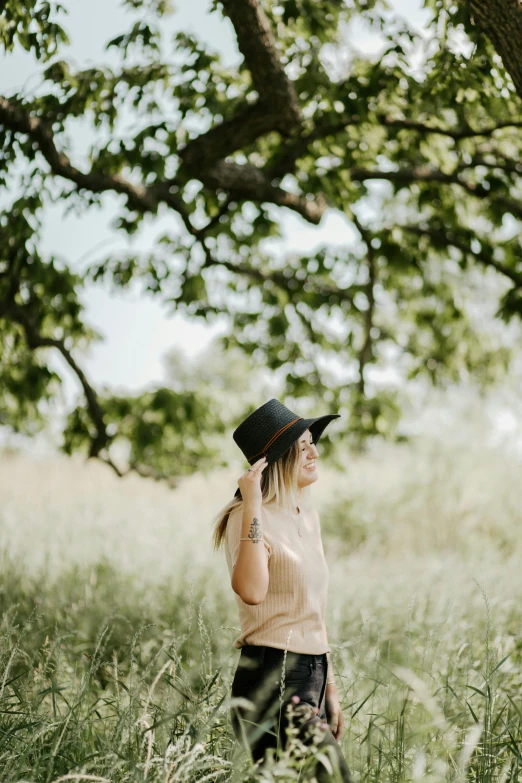 a woman standing in a field of tall grass, black stetson hat, in a tree, curated collections, profile image