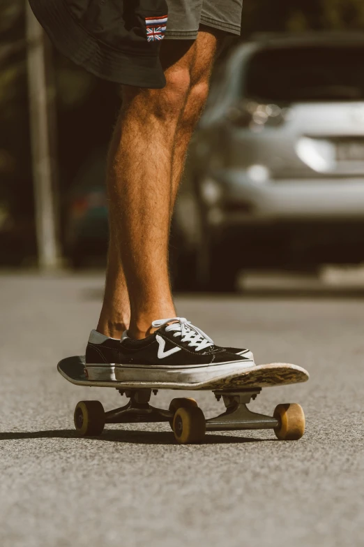 a man riding a skateboard down a street, by Niko Henrichon, pexels contest winner, realism, gray shorts and black socks, 1 2 9 7, trimmed, plain background