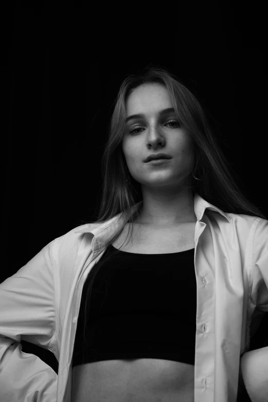 a black and white photo of a woman with her hands on her hips, a black and white photo, inspired by irakli nadar, unsplash, realism, portrait of kim petras, wearing a white button up shirt, portait photo profile picture, studio!! portrait lighting